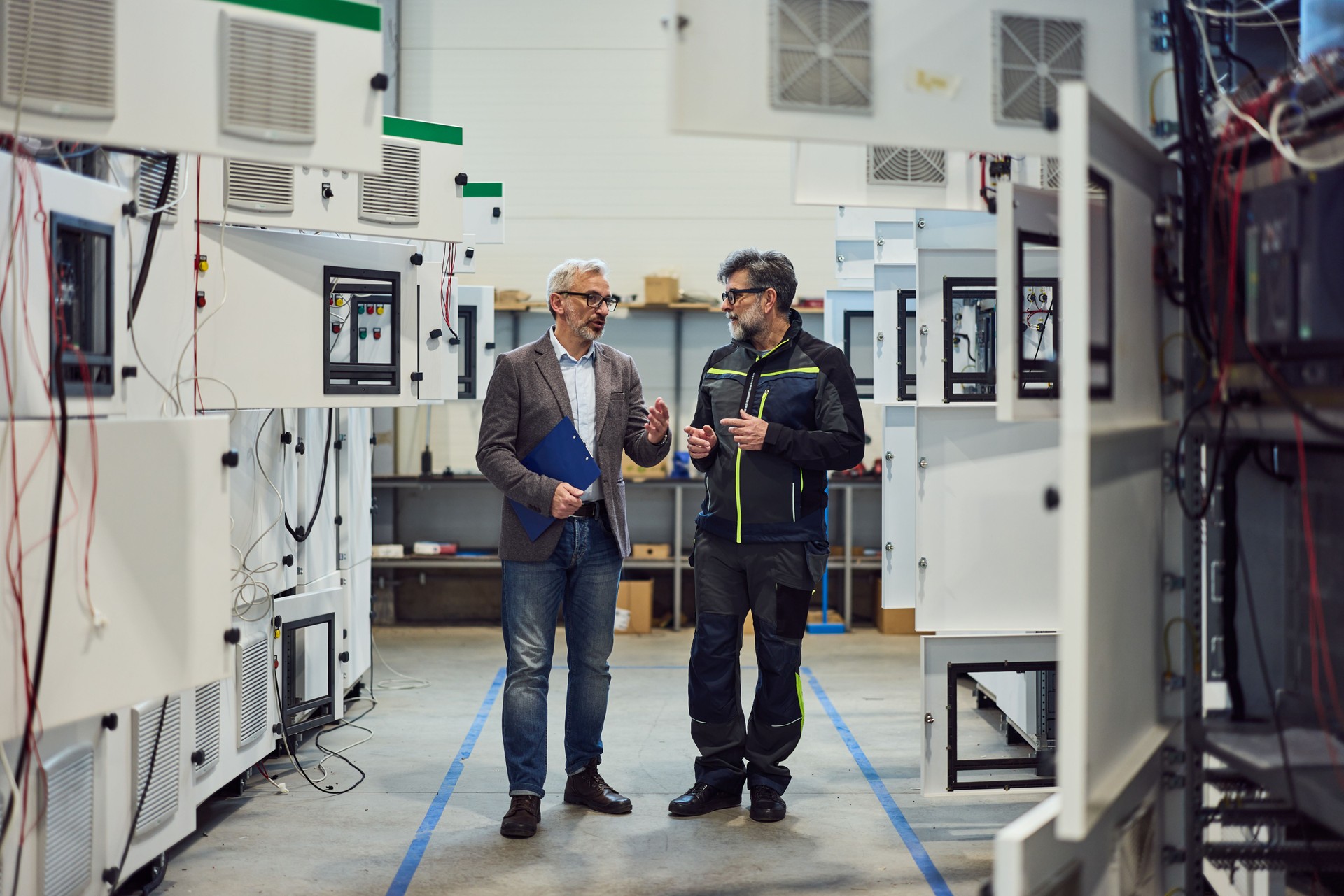 Engineers Discuss Industry Technology in Factory Setting Among Advanced Equipment